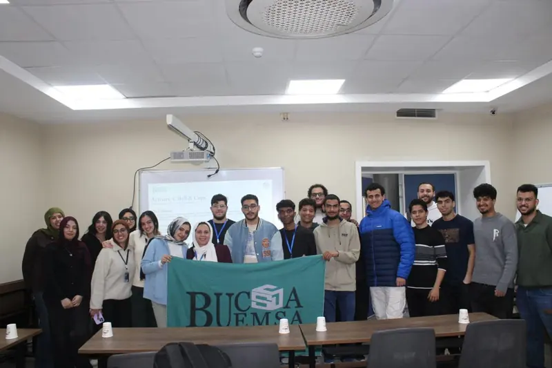 Workshop participants gather behind the BUCSA EMSA flag at the end of Teamwork in Action
